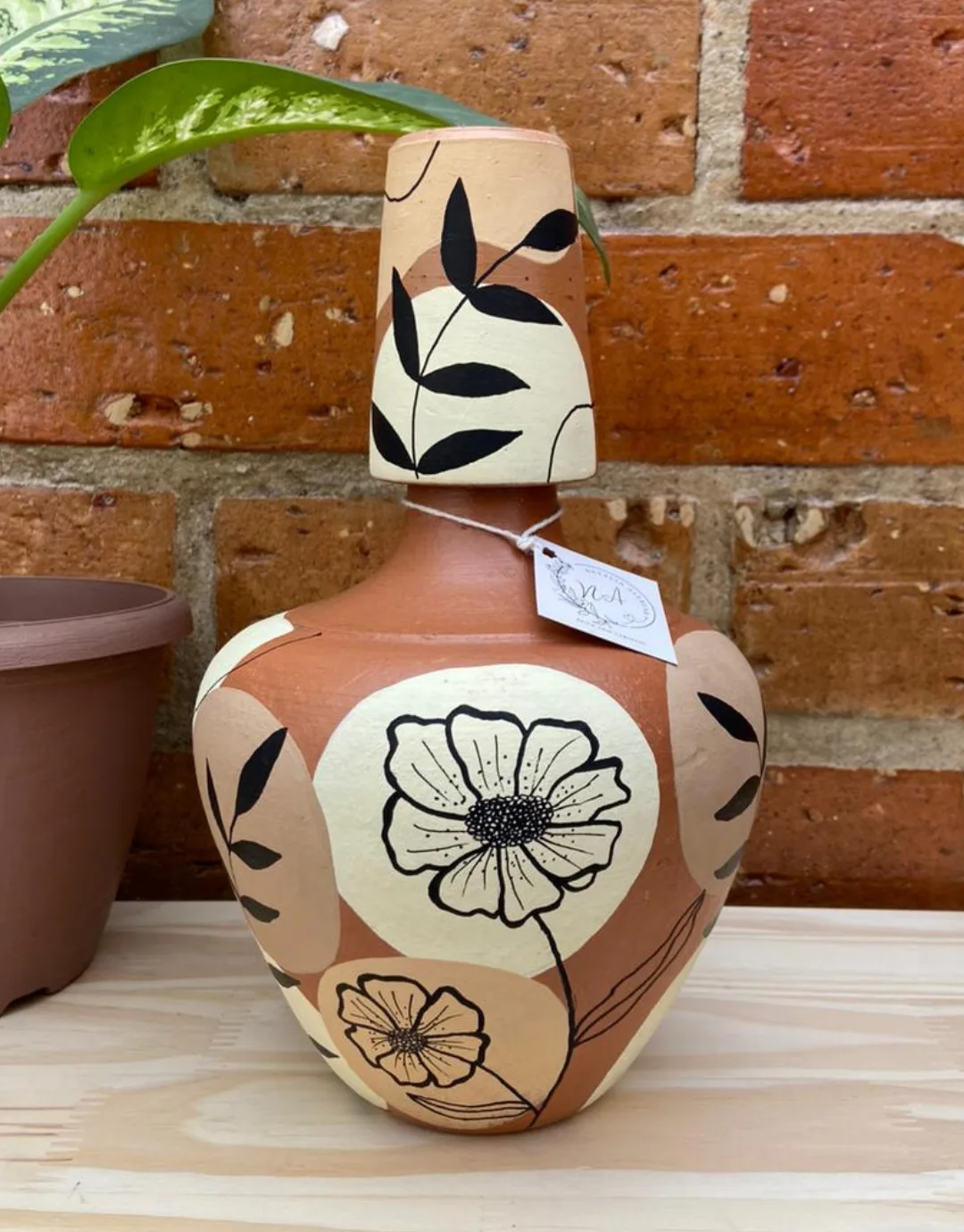Vaso de barro pintado à mão com flores e folhas